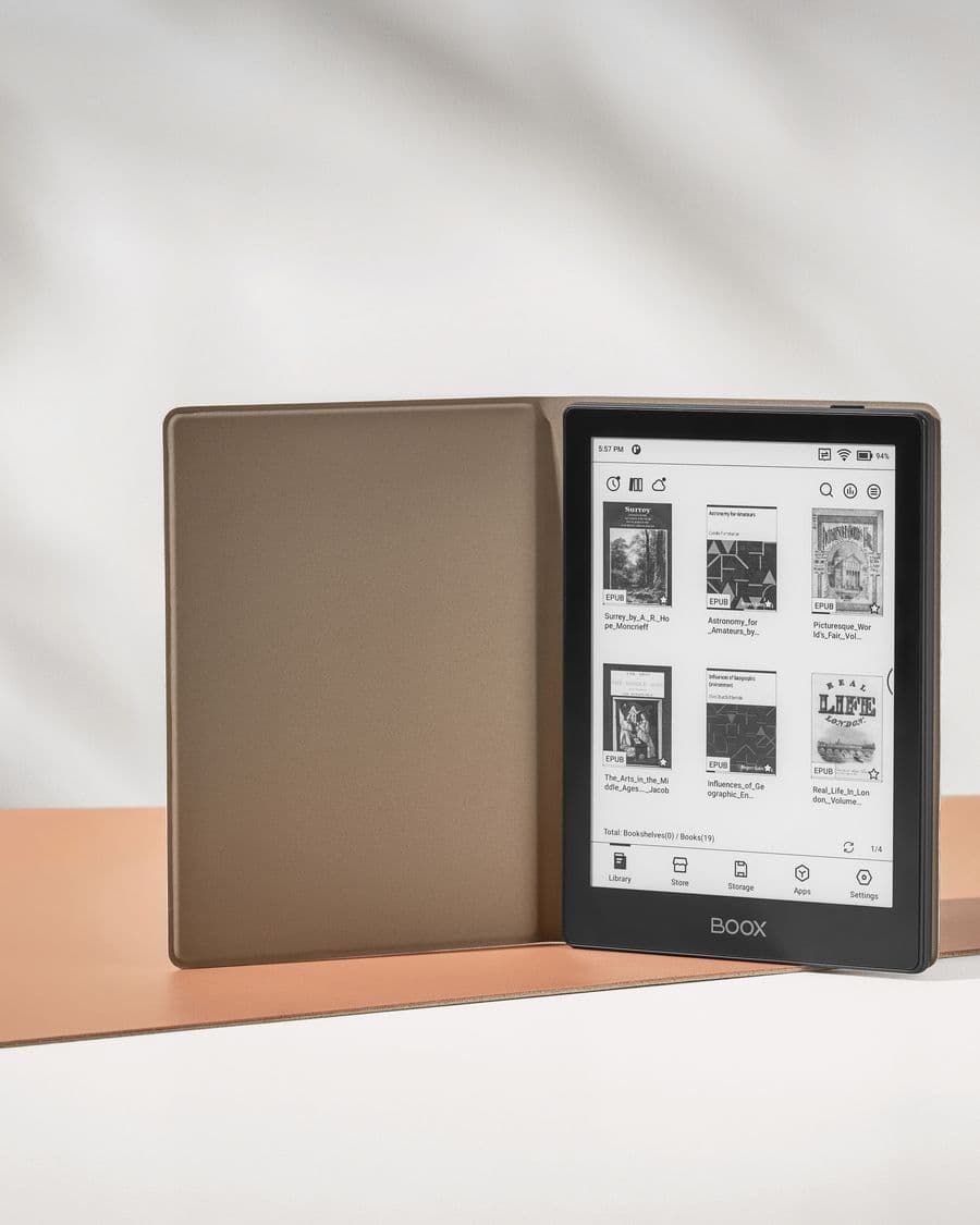 Un BOOX Go 6 noir debout dans son étui ouvert couleur sable, écran de bibliothèque avec des couvertures de livres