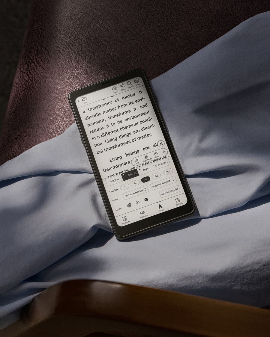 Un BOOX Palma 2 affichant une page de texte avec les réglages de police ouverts, posé sur un lit
