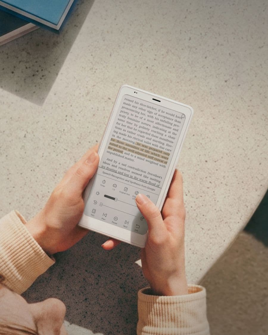 Des mains tiennent un BOOX Palma 2 Pro blanc avec un passage surligné et les commandes de lecture à voix haute ouvertes